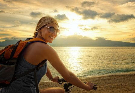 Giovane donna sulla bici in spiaggia